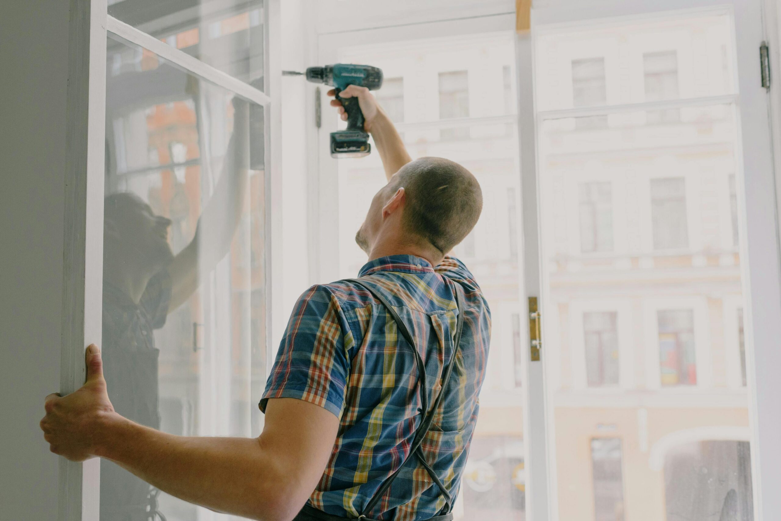 HandyHuman technician drilling window frame during a home repair service