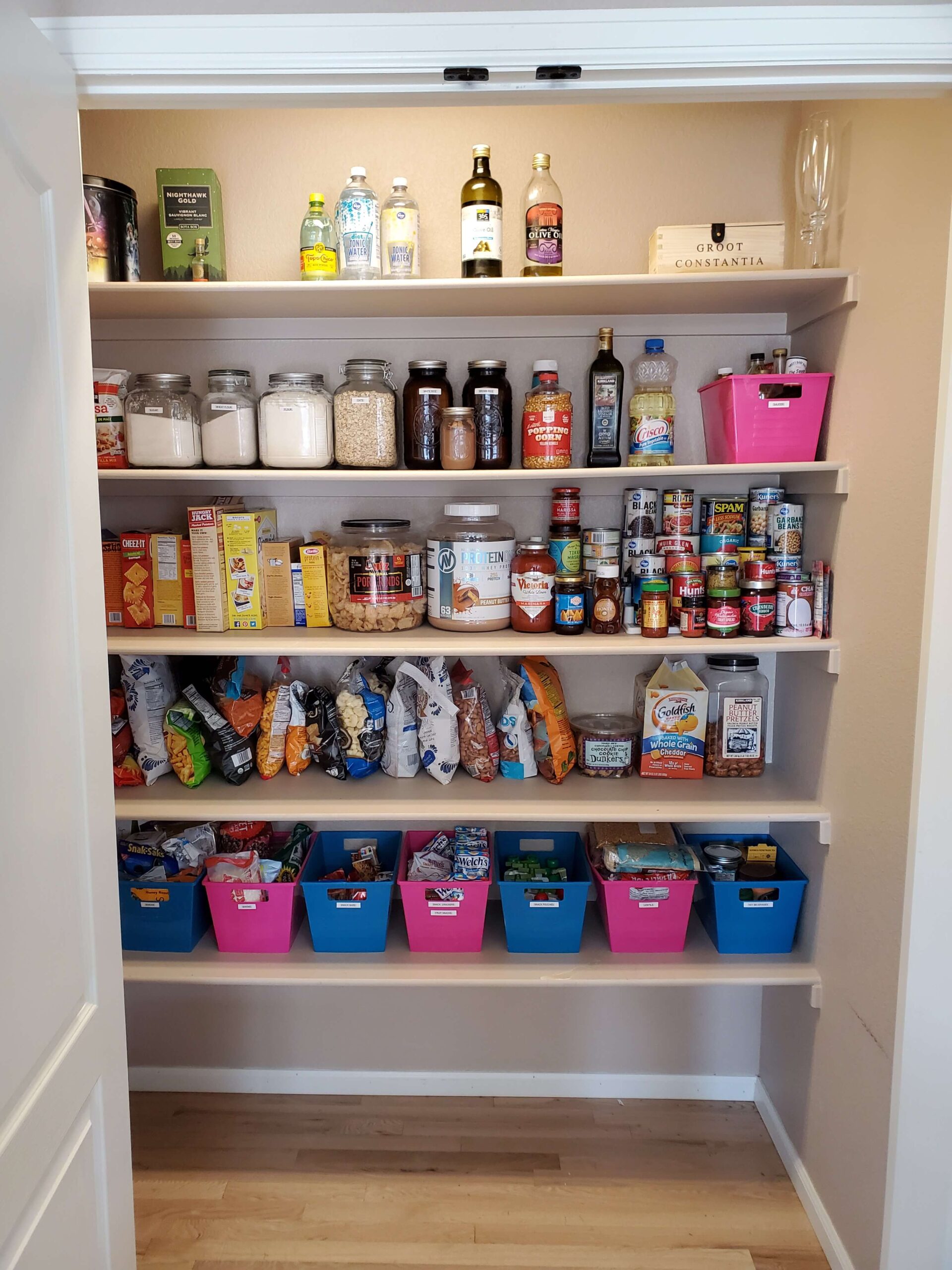 Organized pantry with colorful labeled bins — a visual system designed for neurodivergent minds